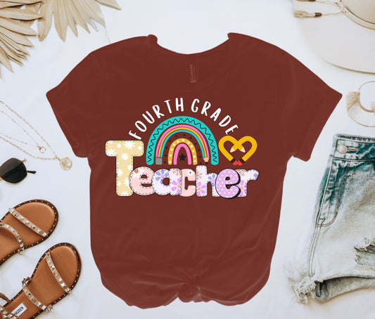 Brown t-shirt with 'Fourth Grade Teacher' text and rainbow design on a light background